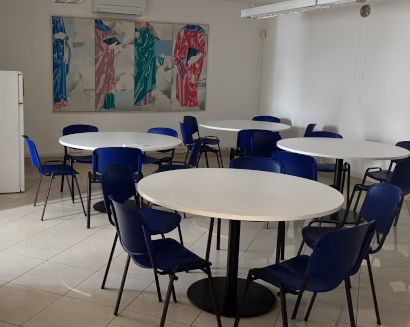 Sala pausa aziendale con tavoli rotondi e sedie per area ristoro